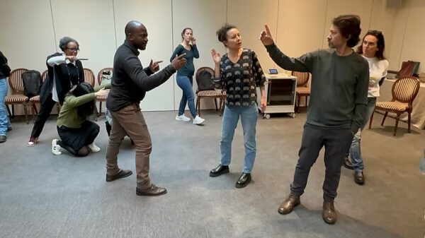 A Participatory Democracy Project in Geneva in 2024. Two men are standing pointing at each other in perhaps a confrontational manner. A woman oversees the performance, directing the legislative theatre performance.